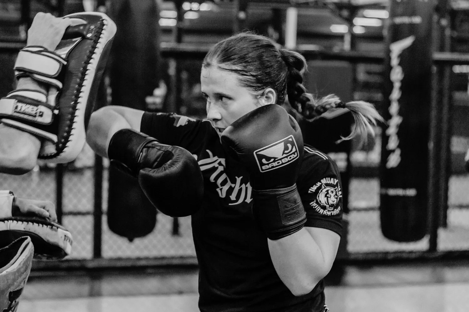 Muay-Thai-Athletin trainiert Schläge an Pratzen, Schwarz-Weiß-Nahaufnahme