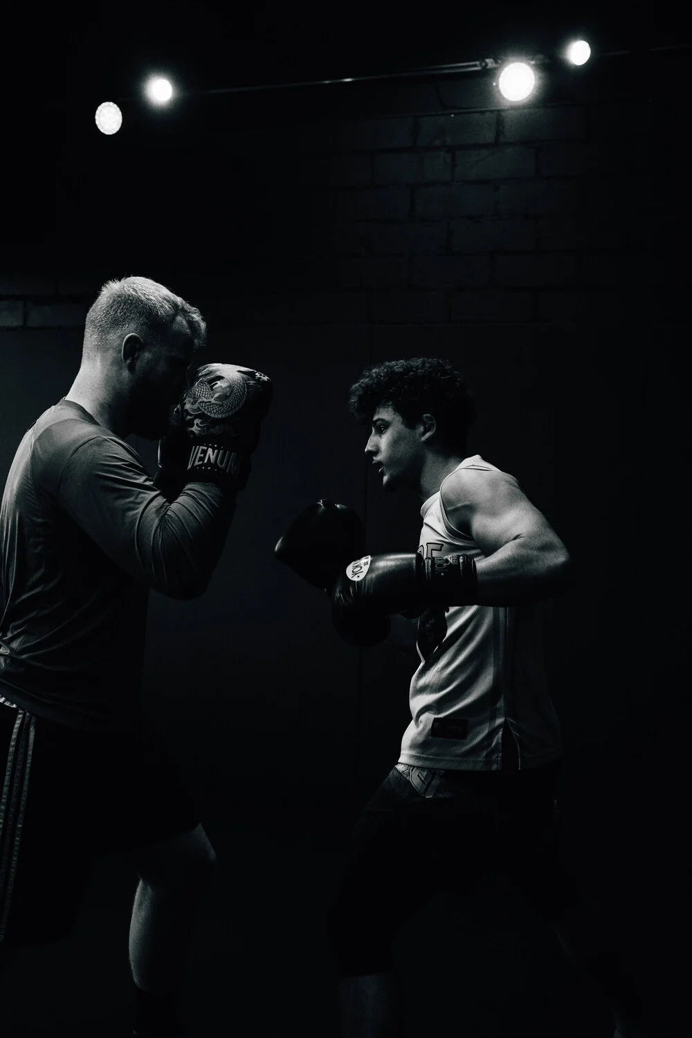Zwei Boxer beim Pratzentraining im dunklen Gym